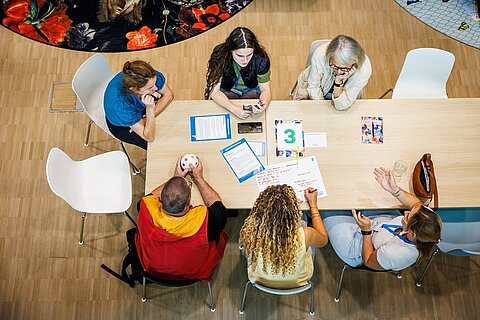 Een tafel met mensen in overleg, van bovenaf gezien