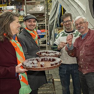 Burgemeester Fleur Gräper gaat rond met drankjes tijdens haar bezoek aan de bouwhal van de carnavalswagens.
