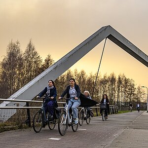 De burgemeester op de fiets over een brug in de Reeshof.
