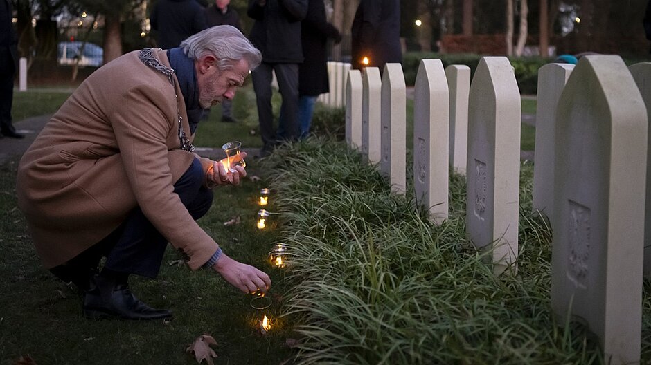 Waarnemend burgemeester Onno Hoes steekt op kerstavond lichtjes aan bij de graven van geallieerde militairen aan de Gilzerbaan.