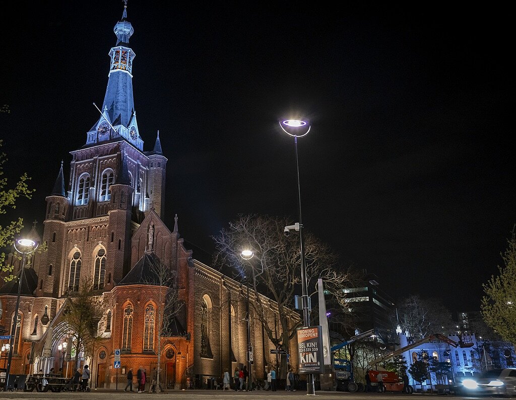 Verlichte kerk in het donker met op de achtergrond het paleis-raadhuis