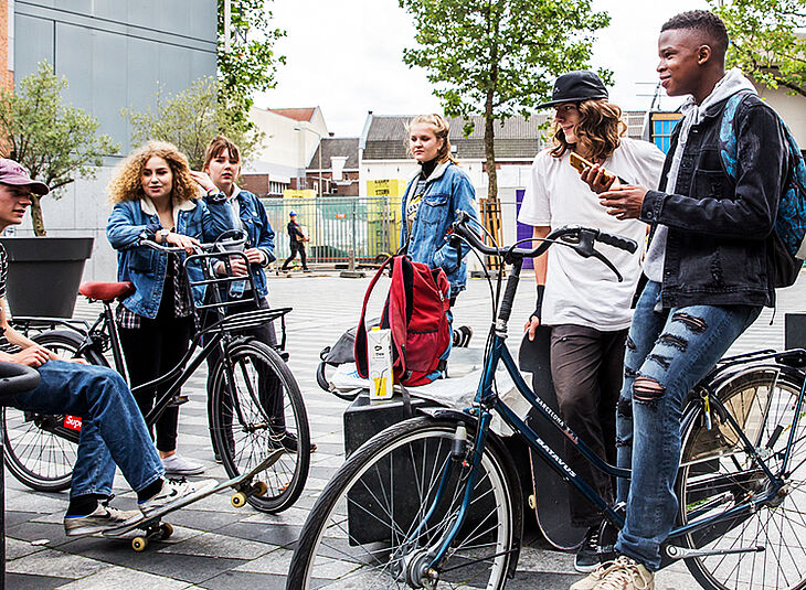 Jongeren op de fiets en zittend bij een plein