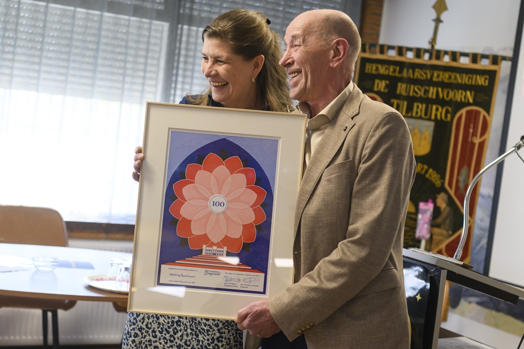 De burgemeester en de voorzitter laten samen de Tilburgse Ereprent zien.