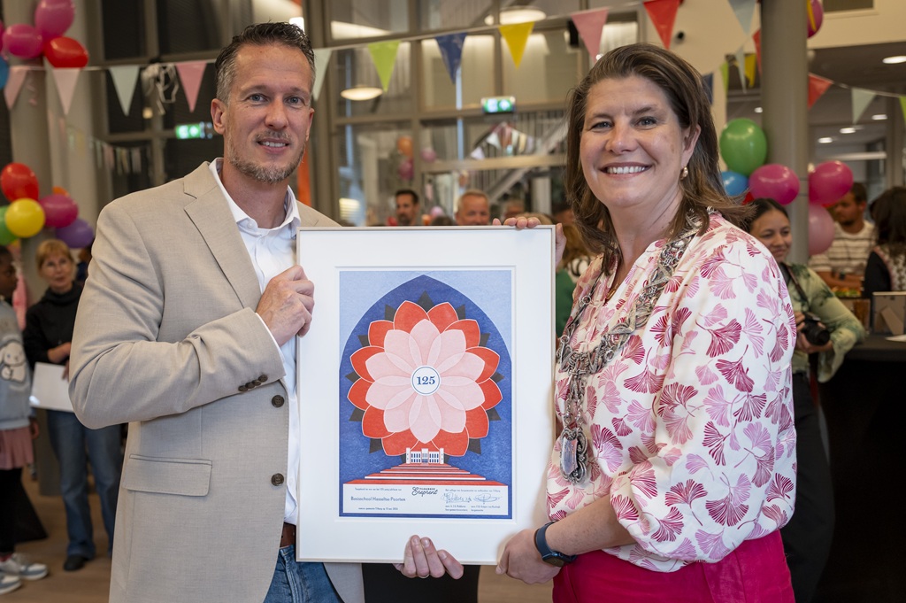 De directeur van de school samen met de burgemeester met de ereprent in hun handen in de Hasseltse Poorten