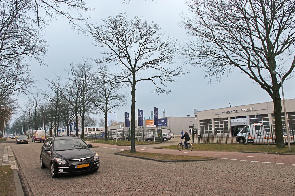 Bedrijventerrein Kraaiven waar een auto voorbij de garage van Peugeot rijdt