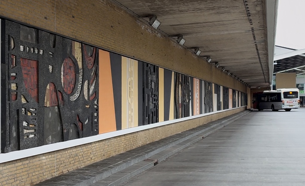Een foto van het kunstwerk, met op de achtergrond een bus en het station