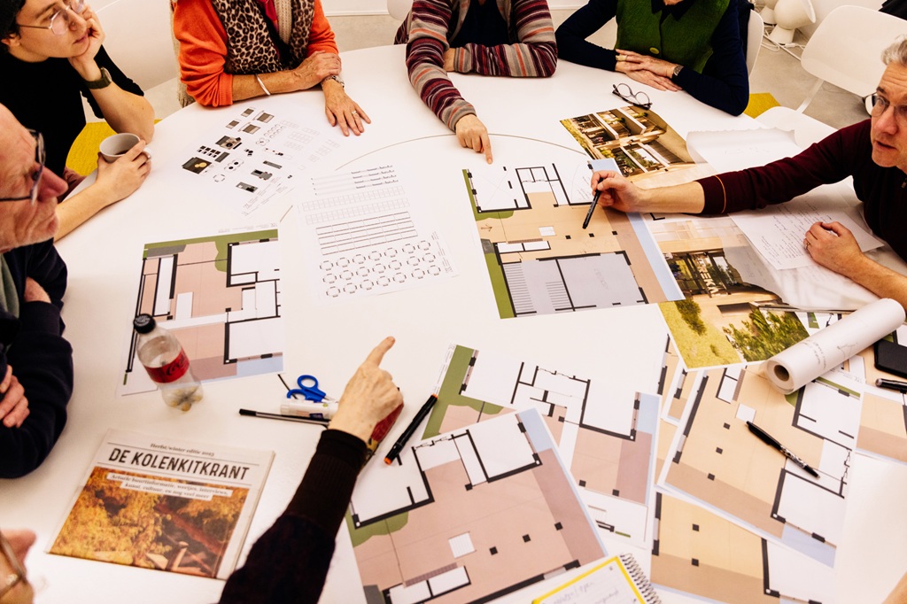 Mensen aan een tafel vol bouwplannen 