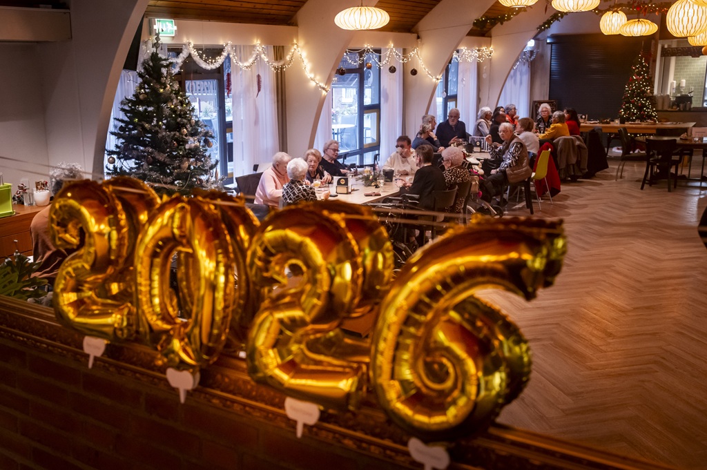 Een zaaltje met ouderen met op de voorgrond een 2026-ballon