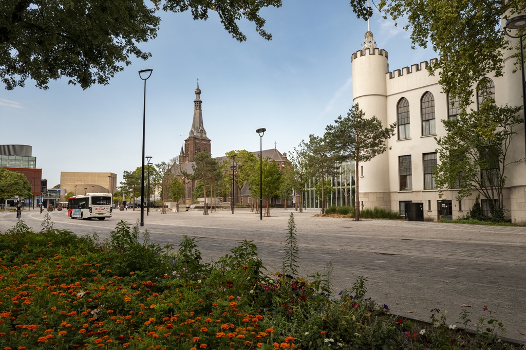 Blik op het Stadsforum met veel groen en de Heikese kerk op de achtergrond